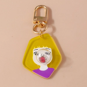 Macro detail of cartoon bubble-blowing girl acrylic keychain with golden metal clasp