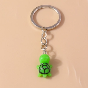 Detail view of a cute green turtle keychain with a silver metal ring for bags