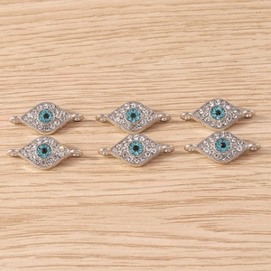 Macro shot of silver evil eye charms with white and blue rhinestones for DIY jewelry making
