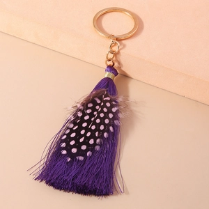 Detail of elegant bohemian keychain with purple silk tassel and spotted purple feather charm