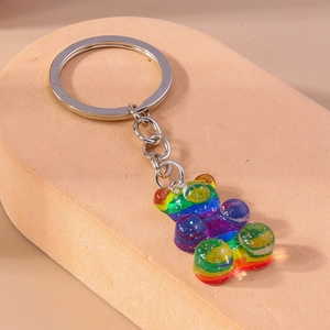 Détail macro d'un charm ours en résine arc-en-ciel avec paillettes et anneau métal
