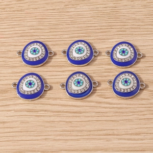 Detailed view of six hamsa evil eye charms with rhinestones on a warm wood surface