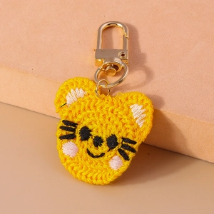 Détail d'un porte-clés tigre crocheté à la main avec fermoir doré sur fond rose