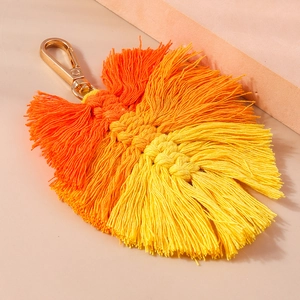 Macro detail of handmade woven leaf keychain with orange gradient cotton cord and gold clasp