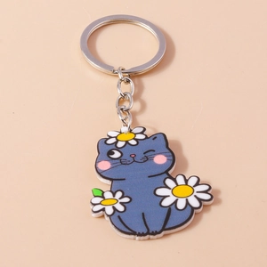 Détail d'un porte-clés chat bleu en acrylique avec motifs marguerites et anneau argenté