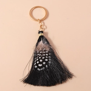 Detail of bohemian keychain with black silk tassel and spotted guinea fowl feathers