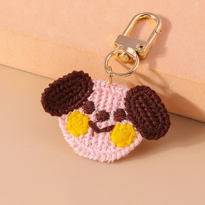 Close-up of pink handmade crochet dog keychain with a polished gold lobster clasp