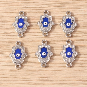 Macro detail of Hamsa Hand and Evil Eye charms with rhinestones on wood background