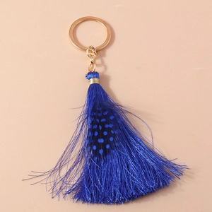 Detail of bohemian dark blue tassel keychain with feather accent and gold metal ring