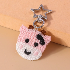 Gros plan sur un porte-clés vache au crochet rose et blanc avec crochet en étoile argentée