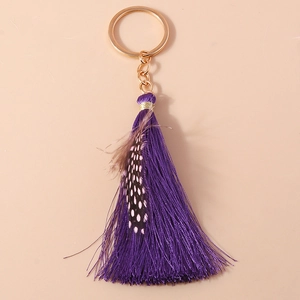 Close-up of purple tassel keychain with golden ring and spotted feather detail