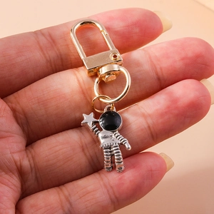Detail view of a silver astronaut pendant with a gold star held in a hand for scale