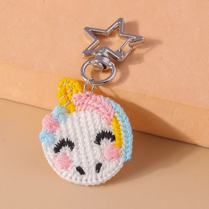 Detail of hand-knit unicorn keychain with star-shaped silver clasp and colorful textures