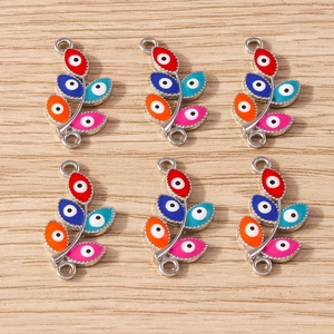 Macro detail of leaf-shaped colorful evil eye jewelry charms on wood background