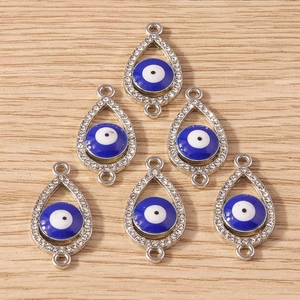 Macro shot of teardrop evil eye pendants with rhinestones on light wood background