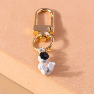 Detail shot of a white spaceman pendant keychain with a golden star and lobster clasp