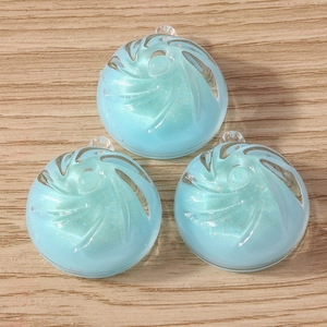Detail of light blue swirl resin charms with glitter for DIY jewelry making