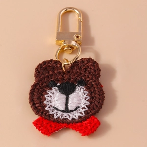 Detailed macro of handmade brown crochet bear keychain with a red bow and gold clasp