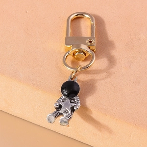 Detail of silver astronaut keychain with black visor, gold clip and star icon