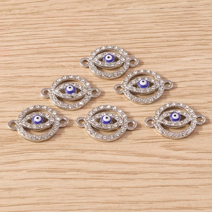 Close-up of circular evil eye charms with white rhinestones on light wood background