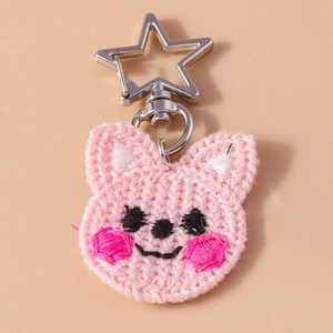 Détail d'un porte-clés chat au crochet rose avec un fermoir métallique en forme d'étoile