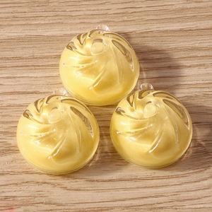 Detailed view of yellow spiral candy pendants with glitter for DIY jewelry crafts