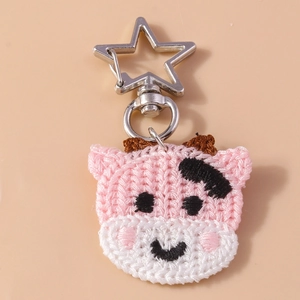 Détail d'un porte-clés vache fait main au crochet avec accents roses et fermoir étoile