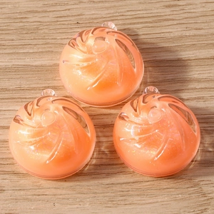 Close-up of translucent orange spiral resin charms with fine glitter for DIY jewelry making