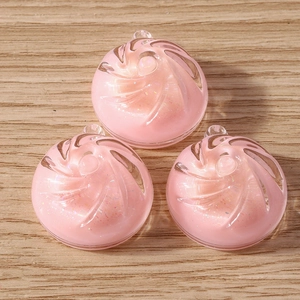 Macro shot of three pink resin spiral charms with glitter on a wooden background