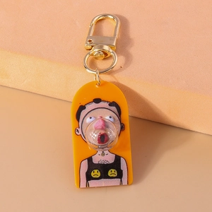 Detail view of yellow acrylic keychain featuring unique cartoon figure blowing bubbles