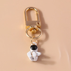 Detail of a golden D-ring clasp holding a white astronaut pendant with a black visor