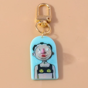 Macro detail of blue acrylic cartoon keychain with gold lobster clasp and smiley vest