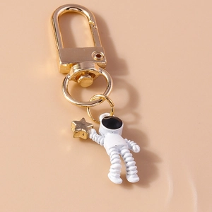 Close-up of white astronaut keychain holding a gold star with a polished D-ring clasp