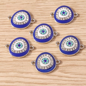Set of 6 blue Evil Eye charms with white rhinestones on light wood background