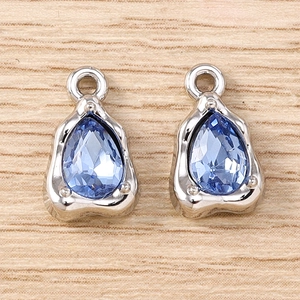 Macro shot of silver drop pendants with light blue gemstones on wooden surface