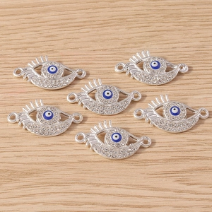 Close-up of evil eye jewelry connectors with rhinestones on a wood background