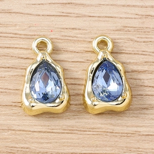 Teardrop blue gemstone pendants with gold frames on light wood grain background
