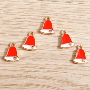 Close-up of gold-plated Christmas hat charms with red and white enamel on wood surface
