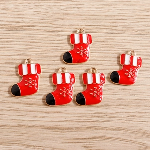 Detailed close-up of four red and white enamel Christmas stocking pendants on wood background