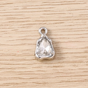 Macro detail of teardrop gem pendant with organic silver frame on wood background