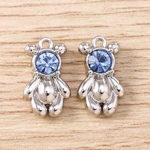 Detailed view of two silver bear charms with blue crystal inlay on wood background