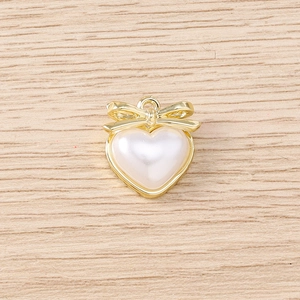 Détail macro du pendentif cœur en perle avec nœud doré et anneau pour bijoux à faire soi-même