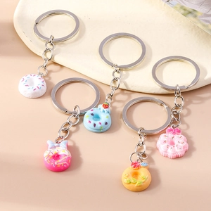 Set of 5 realistic donut food keychains with decorative details on a cream tray