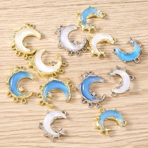 Detail view of crescent moon pendants with zircon accents on a light wood background