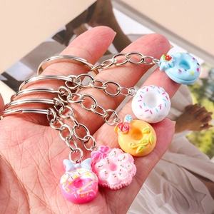 Set of five colorful resin donut keychains with sprinkles and bows held in hand