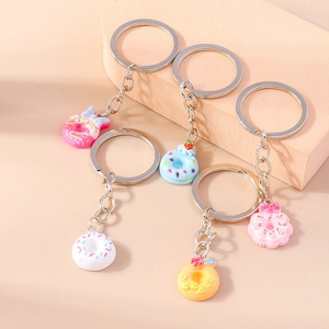 Close-up of five colorful donut keychains with sprinkles and resin charms on neutral cubes