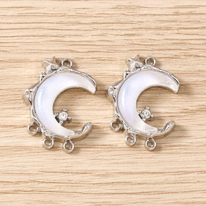Macro shot of silver crescent moon charms with iridescent inlay and sparking rhinestones