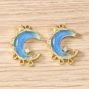 Macro shot of gold crescent moon charms with blue enamel star and sparkly rhinestone