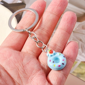 Macro shot of a light blue realistic donut keychain with strawberry and sprinkles decor