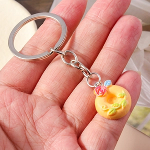 Detailed view of handmade donut keychain with pink rose floral charm in hand